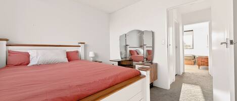 Une chambre à coucher avec un lit, une table de chevet, une lampe et un miroir.