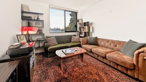 Uma sala de estar moderna com um sofá de couro, uma mesa de centro e uma estante de livros.