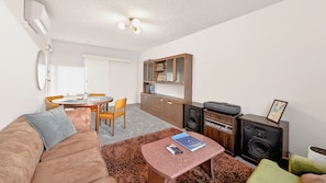 A compact living space with a sofa, a small table, a kitchenette, and a dining area. - 10 mins to Sydney Rd and Lygon St ! Close to the zoo, city, cafes, bar, music ! (Brunswick)