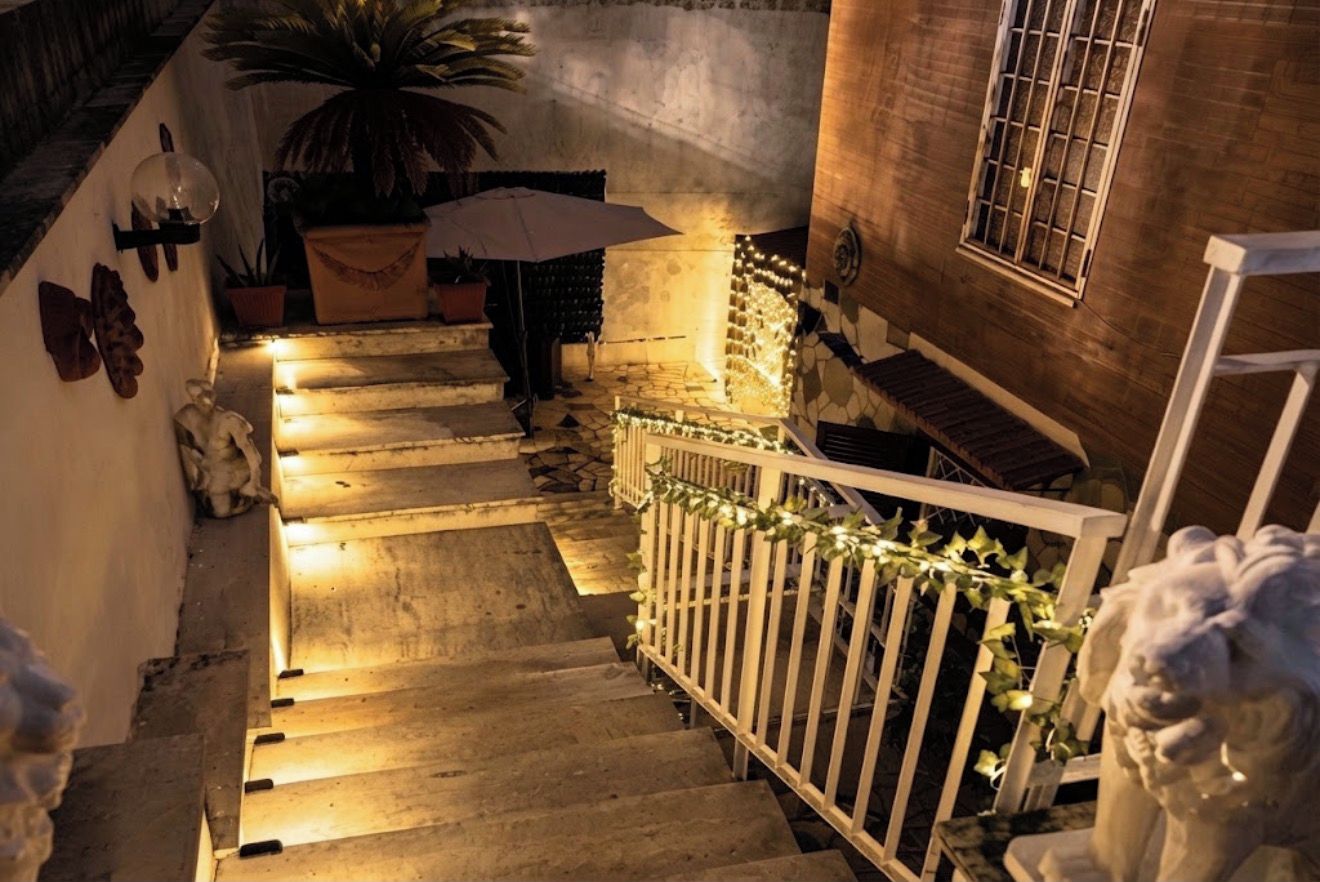 A staircase with a white railing, a potted plant, and a statue at the bottom.