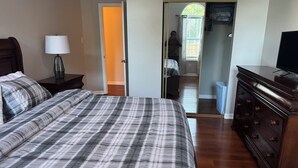 Ein Schlafzimmer mit einem großen Bett, einem Schminktisch, einem Nachttisch und einer Lampe.