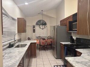 A kitchen with a refrigerator, stove, microwave, and dining table with chairs. - Charming 3-bedroom house with AC in enjoyable Lexington (Lexington)
