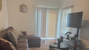 Ein Wohnzimmer mit braunem Ledersofa, einem Couchtisch und einem Fernseher.