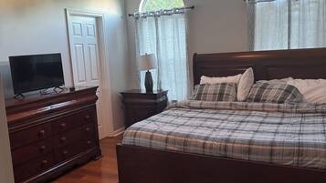 Quarto com cama, cômoda, televisão e ventilador de teto.