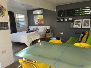 A modern room with a bed, a glass-top table, and a green couch.