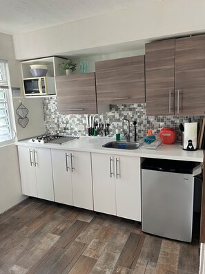 A modern kitchen with white cabinets, a stainless steel dishwasher, and a tiled backsplash.