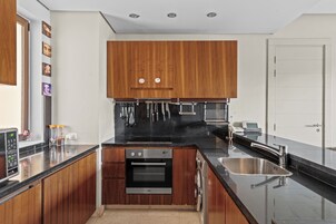 Una cocina moderna con armarios de madera, encimera negra, electrodomésticos de acero inoxidable y horno empotrado.
