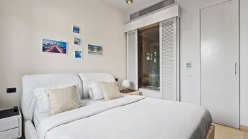 A bedroom with a bed, a nightstand, a wardrobe, and a window with blinds.