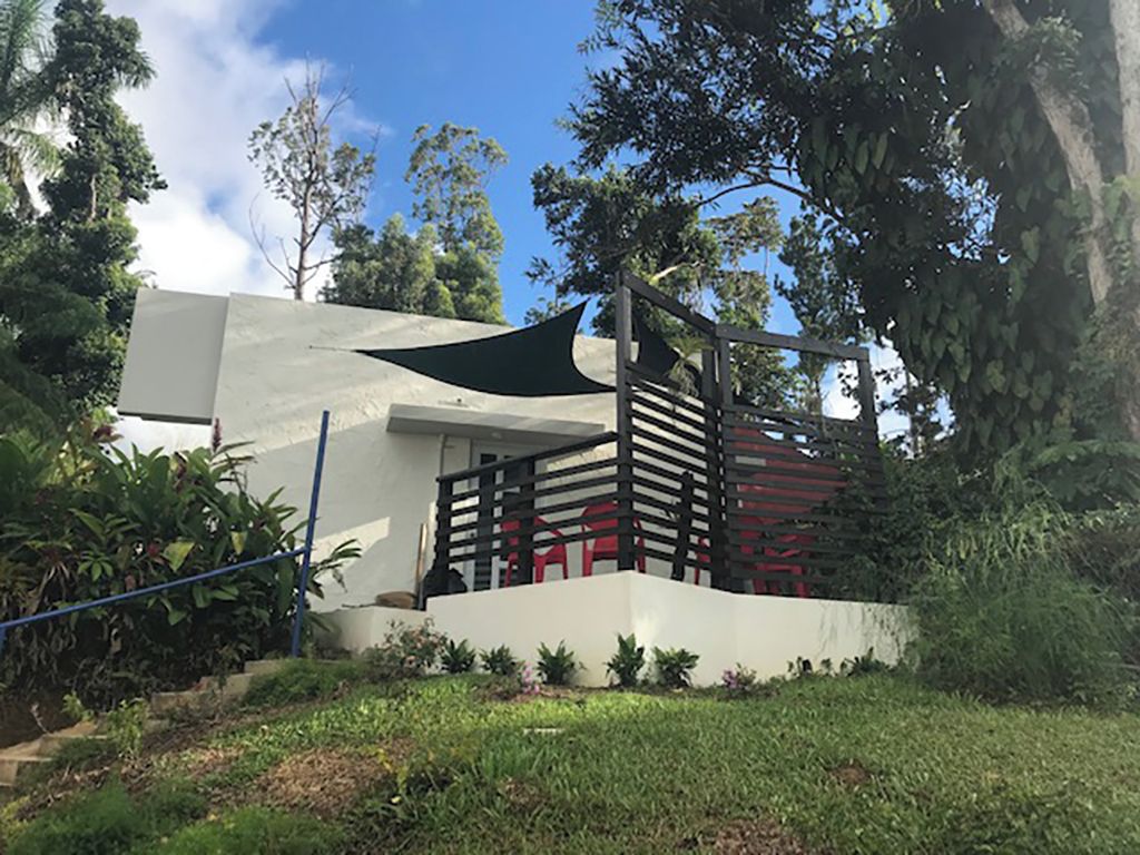 Un edificio moderno con techo plano, balcón con barandilla negra y fachada blanca.