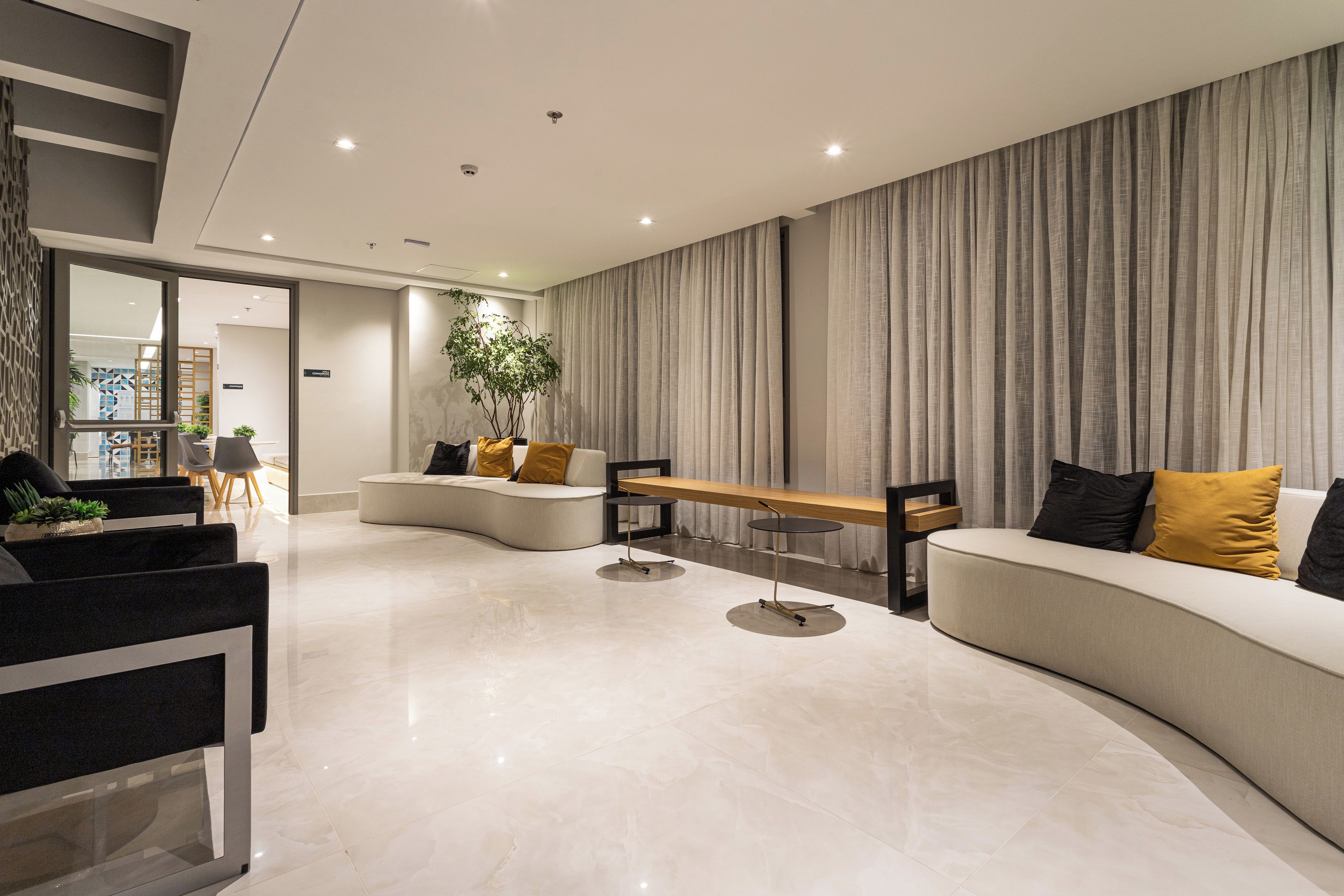 A modern living room with a curved sofa, a small round table, and a potted plant.