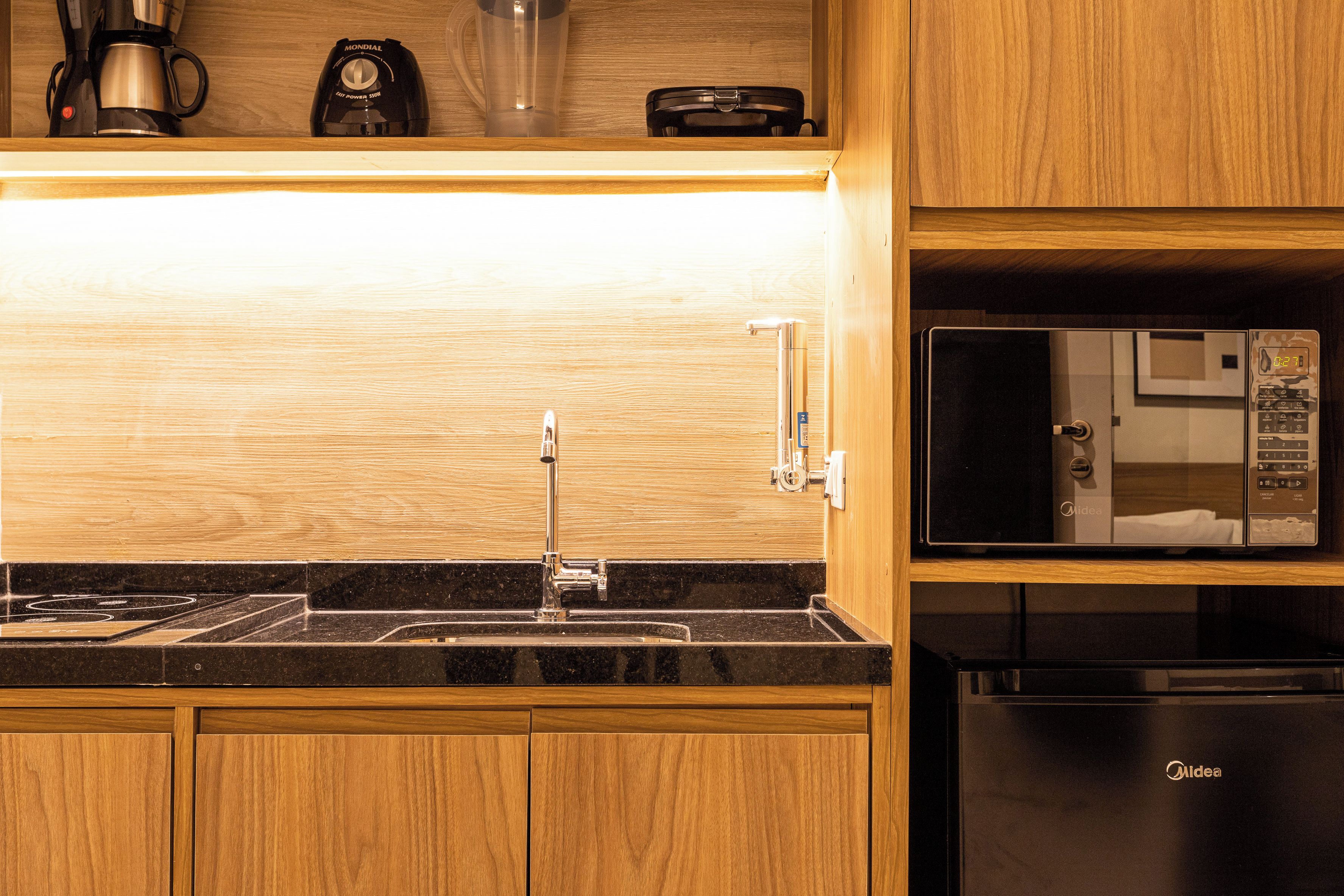 A kitchen with a built-in microwave, a stainless steel sink, and wooden cabinets.