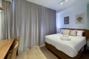 Et hotelværelse med en seng, et træbord og en stol.