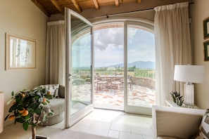 A spacious living area with a sliding glass door leading to an outdoor patio with a table and chairs. - Villa Altavista in Montecarlo (Montecarlo)