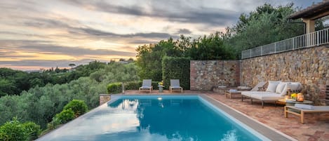 A swimming pool with lounge chairs and a stone wall.