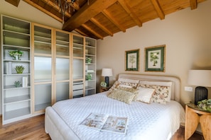 A bedroom with a large bed, a wooden ceiling, a built-in wardrobe, and two framed botanical prints on the wall. - Villa Altavista in Montecarlo (Montecarlo)