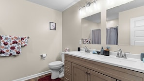 A bathroom with a toilet, sink, mirror, and towel rack. - 4BR Gameday Home + Separate Guest Suite (Tuscaloosa)