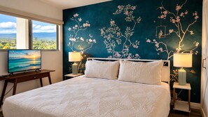 Ein Schlafzimmer mit einem Bett, zwei Nachttischen, einem Fernseher und einer Wandmalerei.