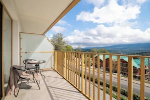 A balcony with a table and chairs, overlooking a road and buildings with green roofs. - Szklarska Poreba | Górna 19A | Air-conditioned Studio | Swimming Pool and Gym (Szklarska Poręba)