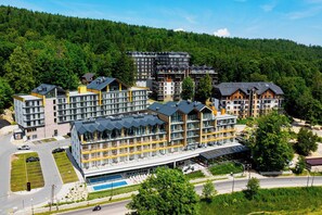 A modern hotel complex with multiple buildings, a swimming pool, and a forested backdrop. - Szklarska Poreba | Górna 19A | Air-conditioned Studio | Swimming Pool and Gym (Szklarska Poręba)