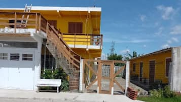 Um edifício de dois andares com escadas que levam a uma varanda, uma garagem branca e uma entrada com portão.