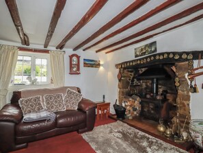 Ein gemütliches Wohnzimmer mit Kamin, Ledersofa und einer rustikalen Steinwand.