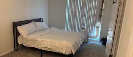 A bedroom with a bed, a radiator, and a door.
