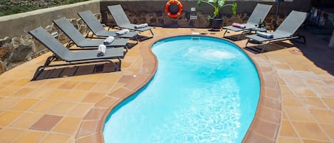 A swimming pool with lounge chairs and a lifebuoy.