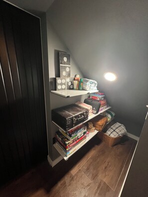 A storage area with shelves holding various items including boxes, a suitcase, and a basket.