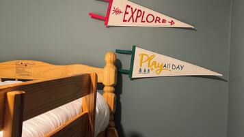 A bed with a wooden headboard and two wall-mounted signs, one red and one yellow, with text.