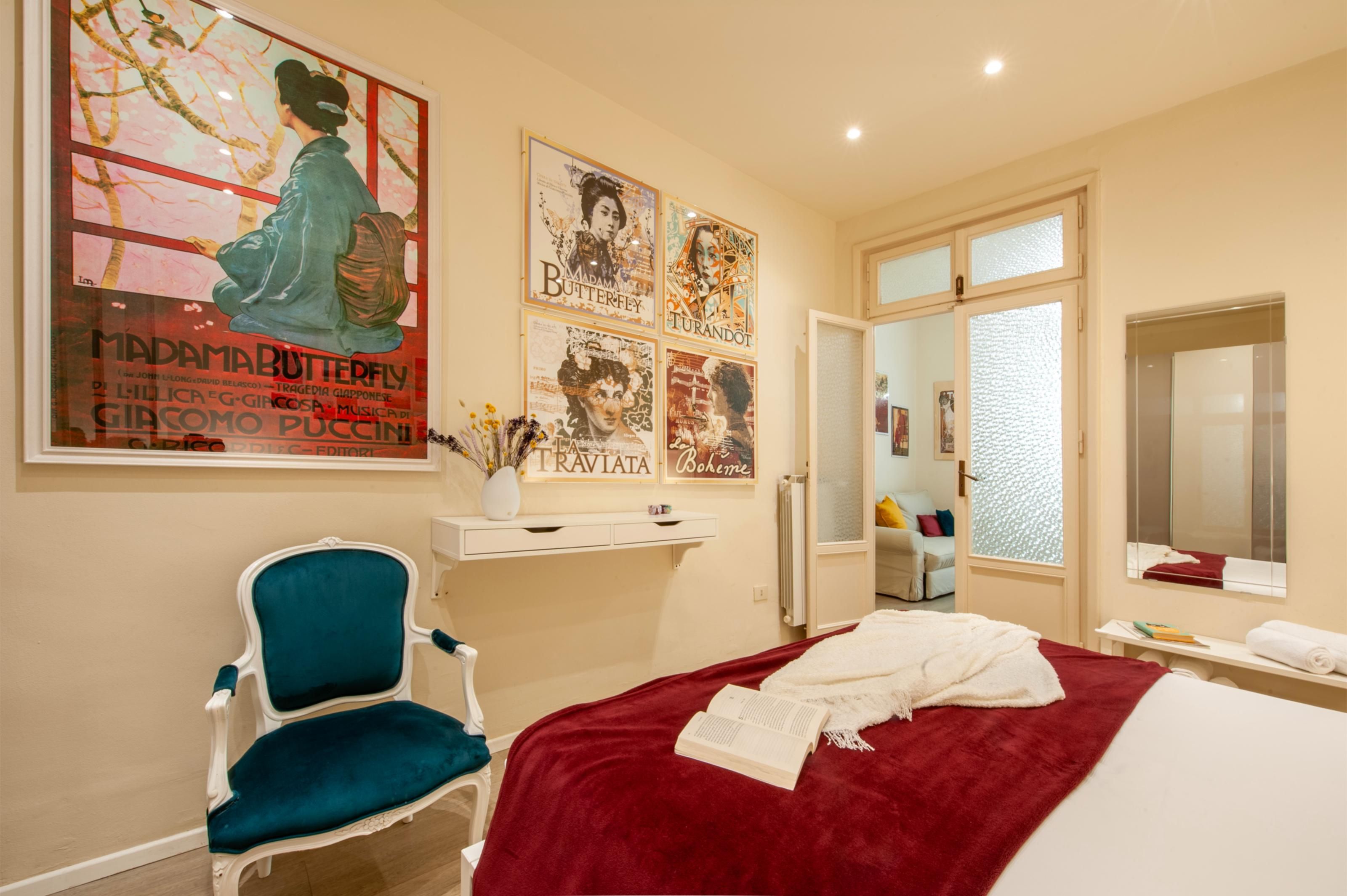 Une chambre d’hôtel avec un lit, une chaise bleue, un bureau blanc et une grande affiche accrochée au mur.