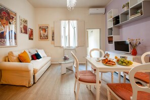 A modern living room with a white sofa, a glass coffee table, and a dining area with a white table and chairs. - Two Minutes from Florence Cathedral   San Lorenzo Terrace (FIRENZE)