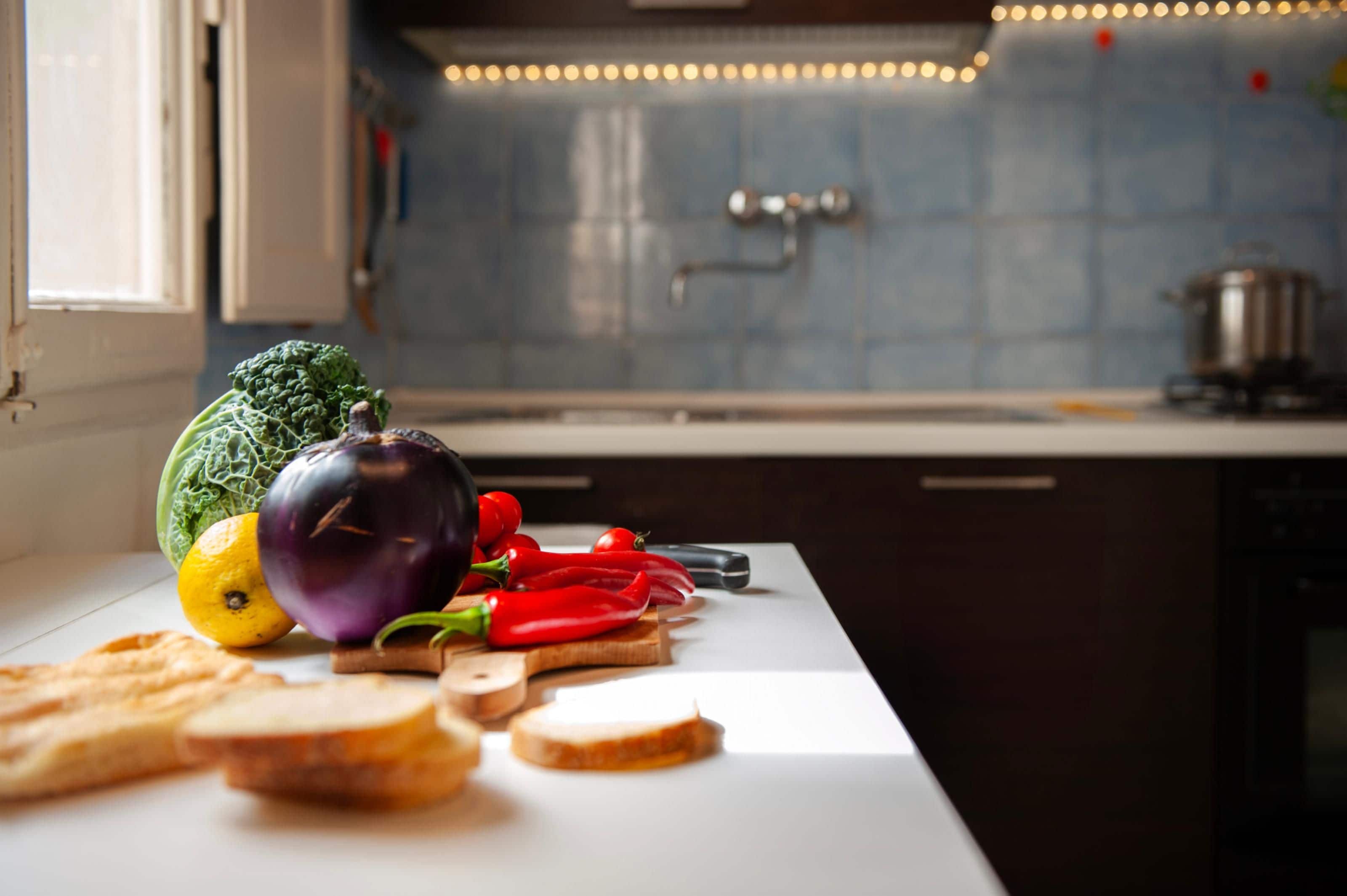 A kitchen counter with vegetables and bread.