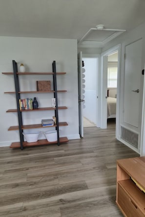 A hallway with a wooden floor, a bookshelf with books and decorative items, and a door leading to another room. - Cozy, family-friendly, 3-bedroom canal-front house in Nokomis 7-min to the beach (Nokomis)