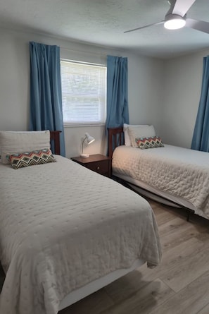A bedroom with two beds, a nightstand, a desk lamp, and a ceiling fan. - Cozy, family-friendly, 3-bedroom canal-front house in Nokomis 7-min to the beach (Nokomis)