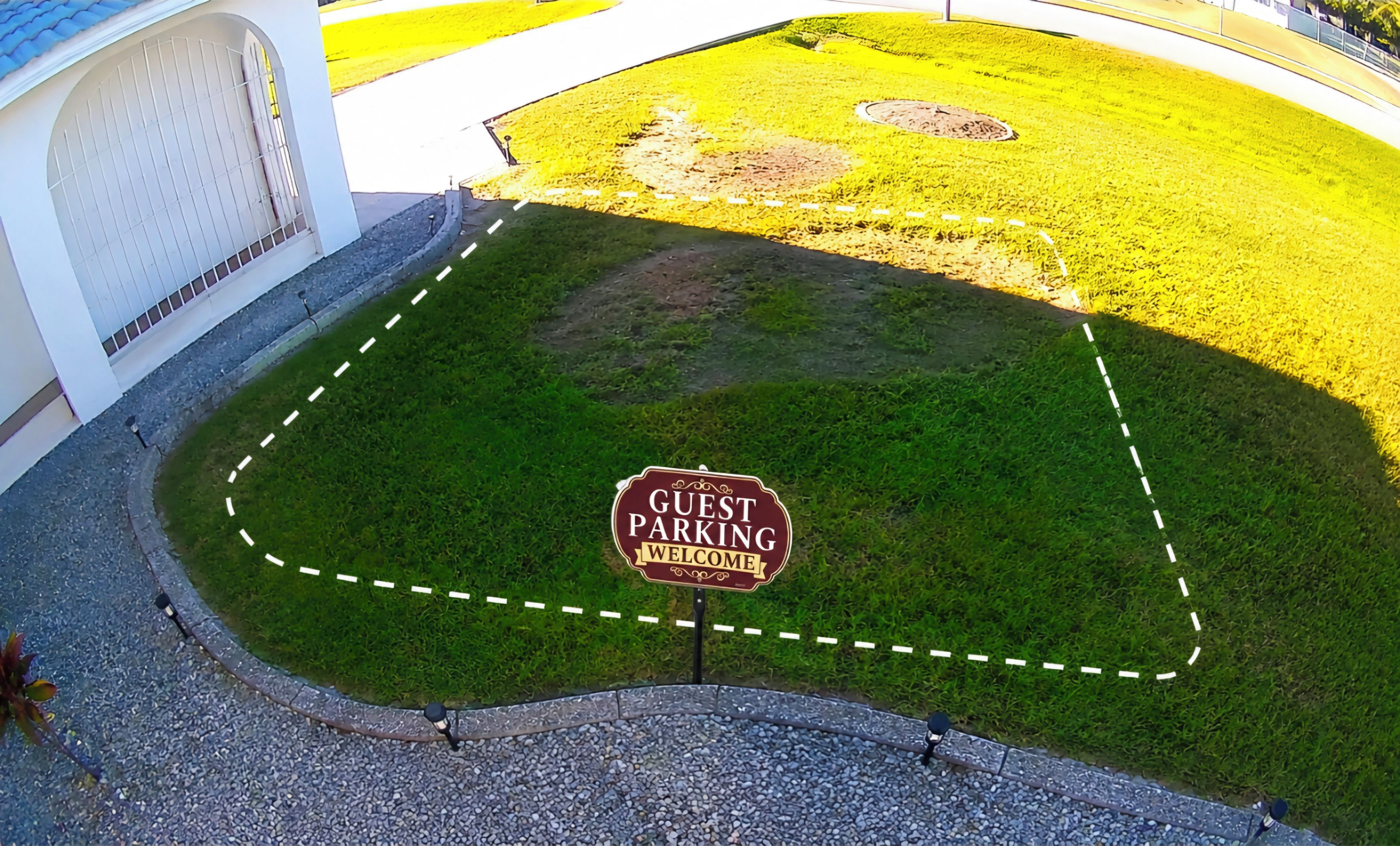 A guest parking area with a welcome sign, a paved path, and a grassy area.