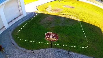 A guest parking area with a welcome sign, a paved path, and a grassy area.