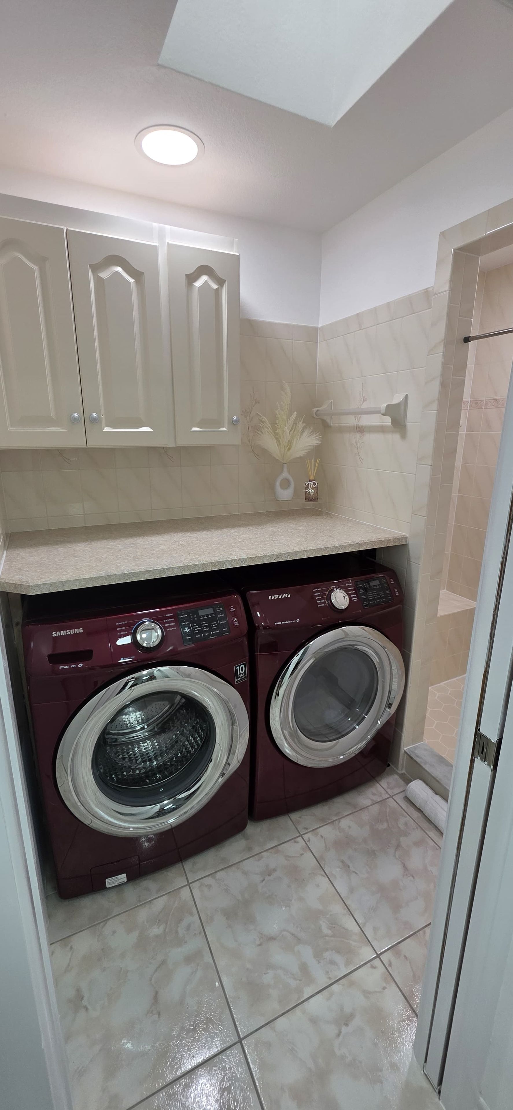 A compact laundry area with two front-loading washing machines, a countertop, and a door with a towel rack.