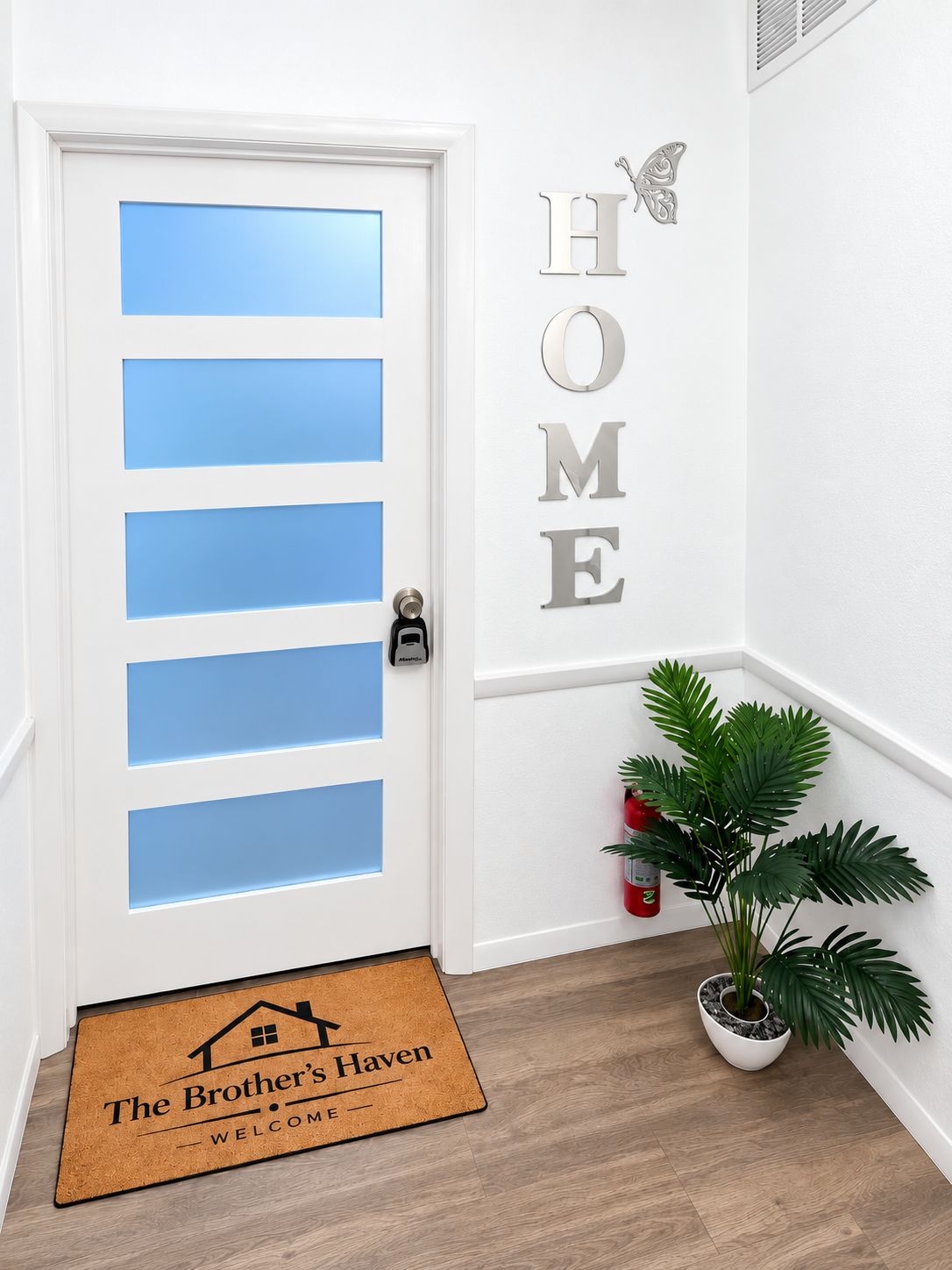 A white door with blue panels, a wall-mounted 'HOME' sign, a doormat with 'The Brother's Haven' text, and a potted plant.