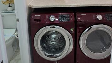 A laundry room with two washing machines, a shelf with a 'laundry' sign, and a toilet visible in the background.