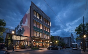 Ett hotell med flera våningar, med en stor och iögonfallande väggmålning på sidan, en restaurang på markplan och en spårvagnslinje i bakgrunden.