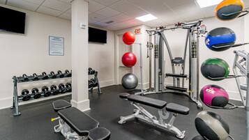 A gym with various exercise equipment, including dumbbells, medicine balls, and weight machines.