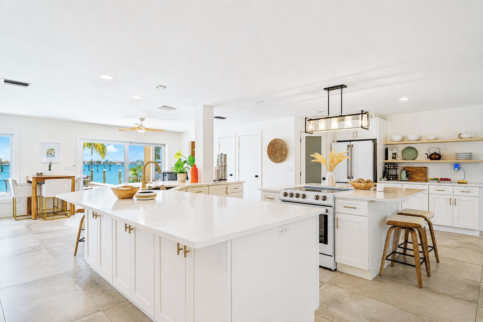 A spacious kitchen with a large island, white cabinetry, and a view of the water.
