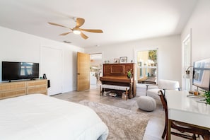 A modern bedroom with a bed, a television, a wooden dresser, a piano, and a desk with a chair. - St Pete Beach Waterfront Pool Hot Tub (St Pete Beach)