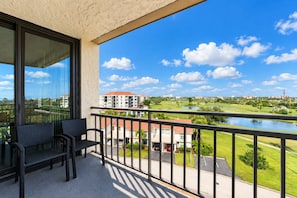 A balcony with a view of a golf course, a building with a red roof, and a clear blue sky. - Bayway Isles Isla Del Sol Bahia Del Mar Pool (St Petersburg)
