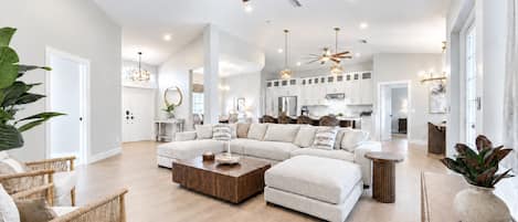 A spacious living area with a large sectional sofa, a coffee table, and a ceiling fan.