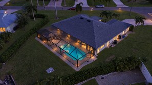 A house with a swimming pool, a covered patio, and a well-maintained lawn. - New Luxury 4BR Gulf-Access Canal Villa with Heated Pool, AC, & Central Location (Cape Coral)