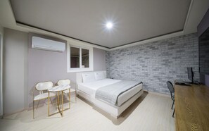 Ein Schlafzimmer mit einem Bett, einem Schreibtisch, zwei Stühlen und einem Fenster.