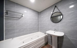 Ein modernes Badezimmer mit Badewanne, Waschbecken und Spiegel.