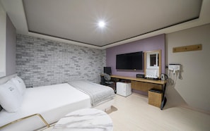 Ein Hotelzimmer mit Bett, Schreibtisch, Computer und einer Backsteinwand.