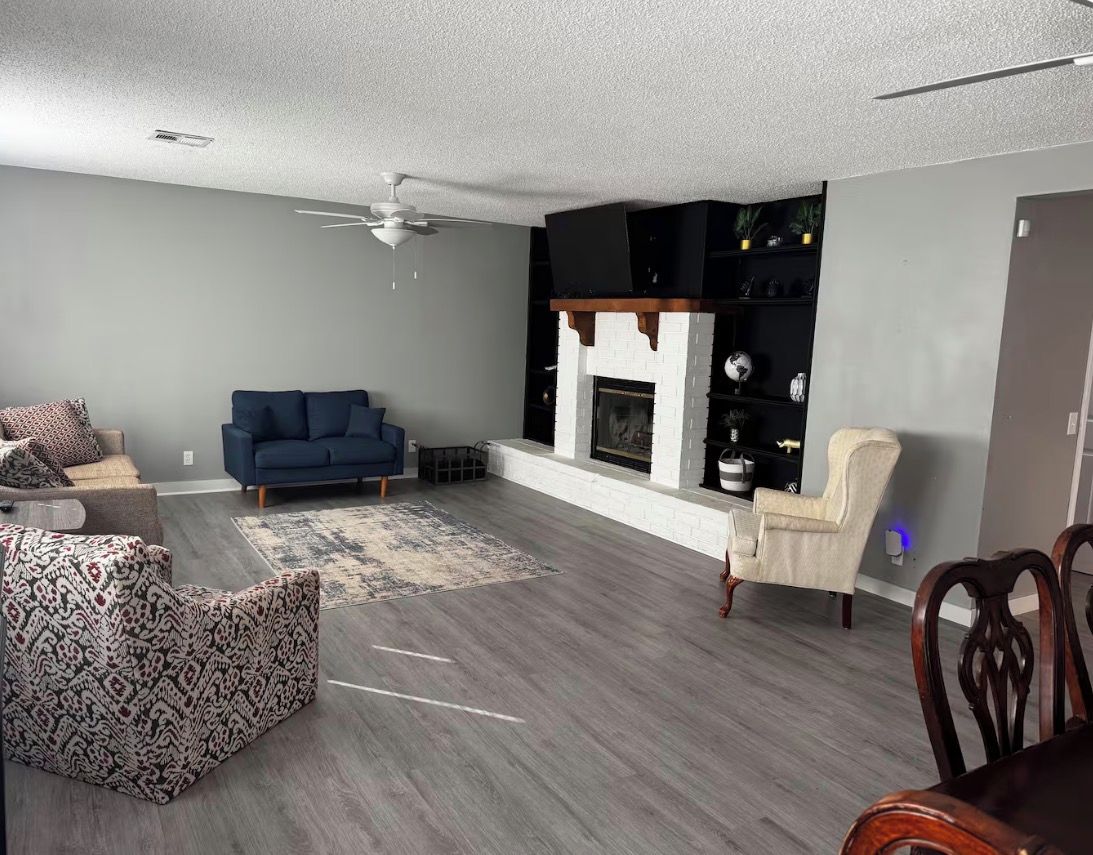 A living room with a blue sofa, patterned ottoman, and a fireplace.